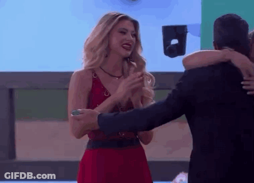 A Woman In A Red Dress Is Hugging A Man In A Black Suit GIF
