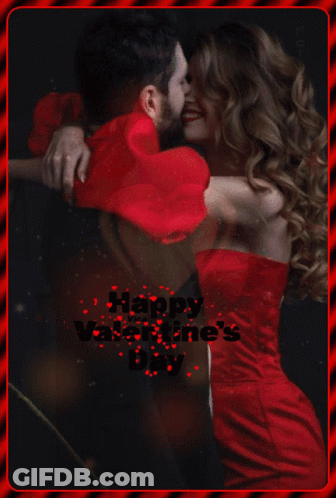 A Woman In A Red Dress Is Hugging A Man In A Red Heart Shaped Pillow GIF