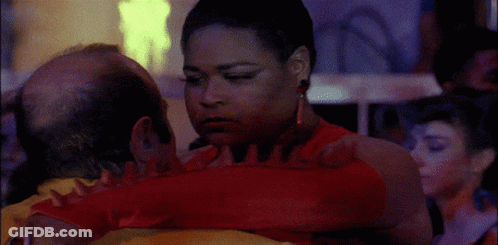 A Woman In A Red Dress Is Hugging A Man With A Bald Head GIF