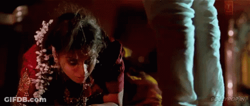 A Woman In A Red Dress Is Kneeling Down Next To A Man . GIF
