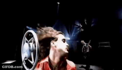 A Woman In A Red Dress Is Laying Down With Her Hair Blowing In The Wind In Front Of A Microphone . GIF