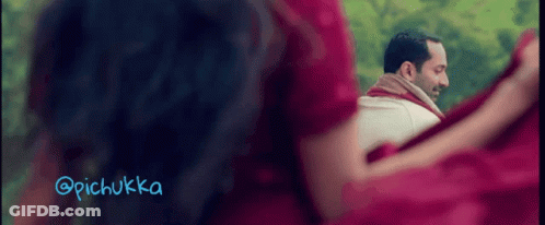 A Woman In A Red Dress Is Looking At A Man In A White Shirt With A Scarf Around His Neck GIF