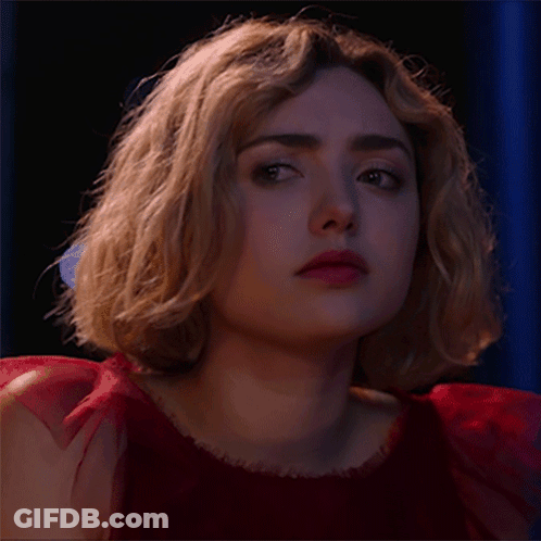 A Woman In A Red Dress Is Looking At The Camera GIF