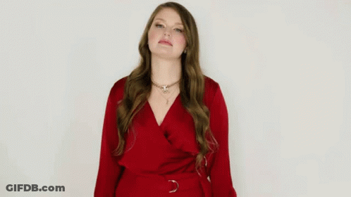 A Woman In A Red Dress Is Making A Funny Face And Giving A Thumbs Up . GIF