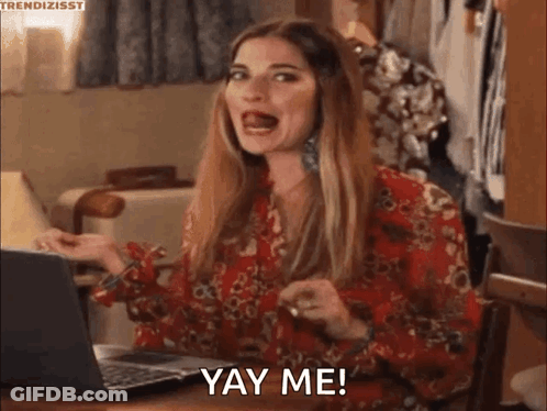A Woman In A Red Dress Is Sitting At A Table With A Laptop And Making A Funny Face . GIF