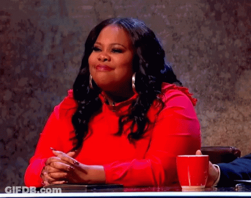 A Woman In A Red Dress Is Sitting At A Table With A Red Cup Of Coffee . GIF