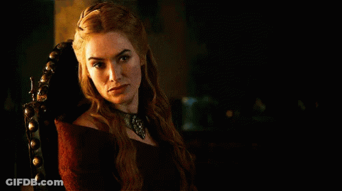A Woman In A Red Dress Is Sitting In A Chair In A Dark Room And Looking At The Camera . GIF