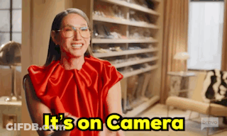 A Woman In A Red Dress Is Sitting In A Chair In Front Of A Closet . GIF