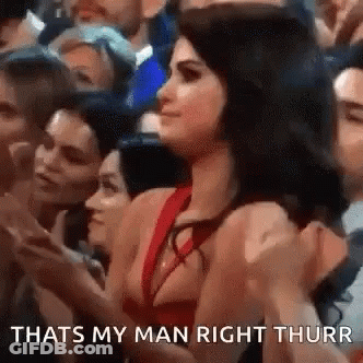 A Woman In A Red Dress Is Sitting In A Crowd . GIF