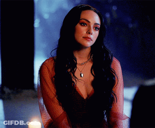 A Woman In A Red Dress Is Sitting In Front Of A Candle GIF