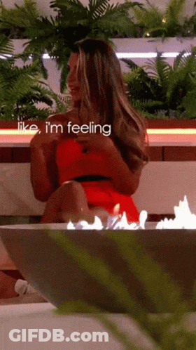 A Woman In A Red Dress Is Sitting In Front Of A Fire With The Words Like I 'M Feeling Above Her GIF