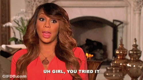 A Woman In A Red Dress Is Sitting In Front Of A Fireplace And Talking . GIF