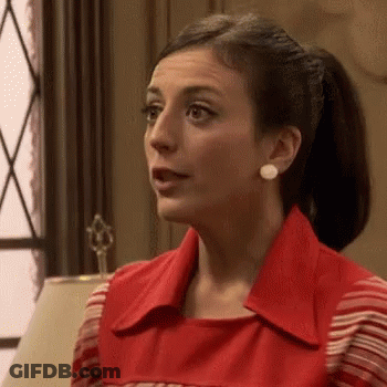 A Woman In A Red Dress Is Sitting In Front Of A Lamp In A Room . GIF