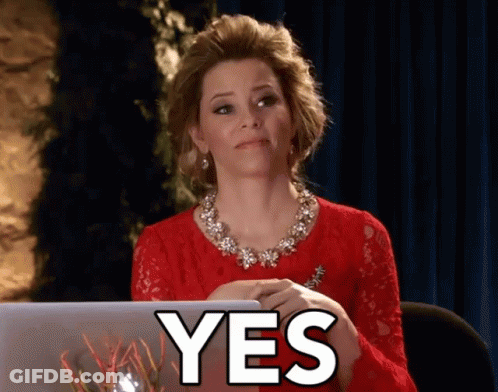 A Woman In A Red Dress Is Sitting In Front Of A Laptop And The Word Yes Is On The Screen GIF