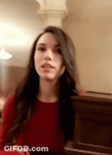 A Woman In A Red Dress Is Sitting In Front Of A Piano And Making A Funny Face . GIF