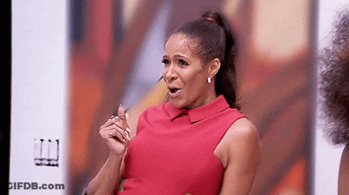 A Woman In A Red Dress Is Sitting In Front Of A Screen . GIF