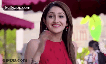 A Woman In A Red Dress Is Smiling While Standing In Front Of A Restaurant . GIF