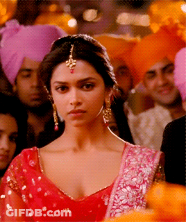 A Woman In A Red Dress Is Standing In A Crowd Of People GIF