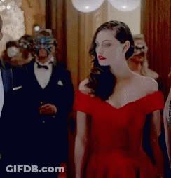 A Woman In A Red Dress Is Standing In A Hallway With People In Masks GIF