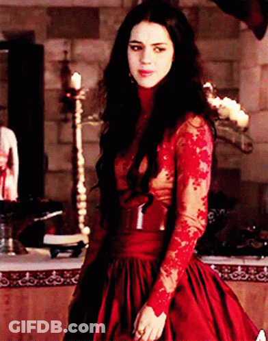 A Woman In A Red Dress Is Standing In A Room GIF