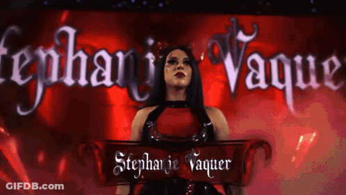 A Woman In A Red Dress Is Standing In Front Of A Banner That Says Stephanie Vaquer GIF
