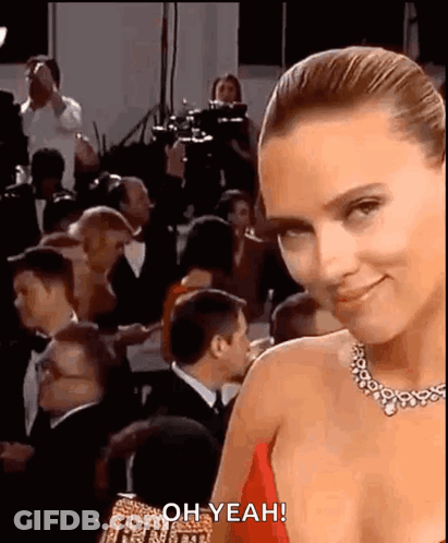 A Woman In A Red Dress Is Standing In Front Of A Crowd Of People At An Event . GIF
