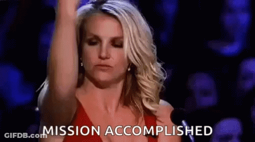 A Woman In A Red Dress Is Standing In Front Of A Crowd With Her Arm In The Air And The Words Mission Accomplished . GIF