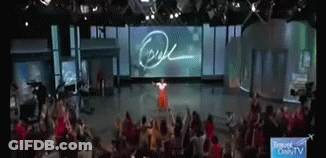 A Woman In A Red Dress Is Standing In Front Of A Large Screen That Says Ryan GIF