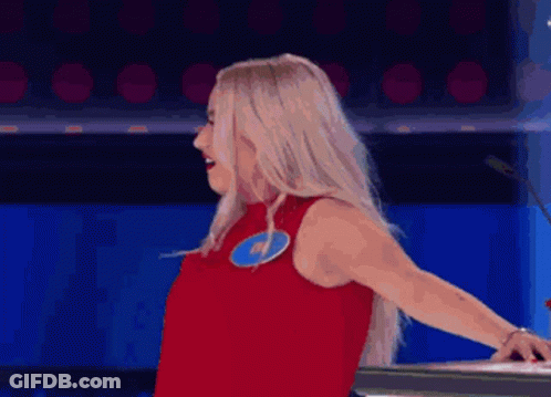 A Woman In A Red Dress Is Standing In Front Of A Microphone And Making A Funny Face . GIF