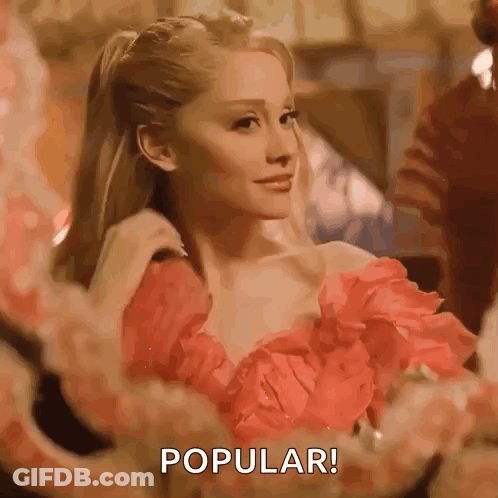 A Woman In A Red Dress Is Standing In Front Of A Mirror And Saying `` Popular '' . GIF