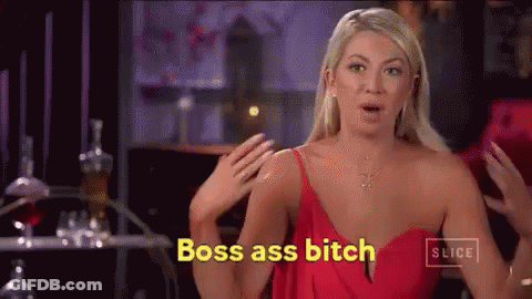 A Woman In A Red Dress Is Standing In Front Of A Table And Says Boss Ass Bitch . GIF