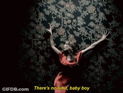 A Woman In A Red Dress Is Standing In Front Of A Wall With Flowers And The Words There 'S No Limit GIF