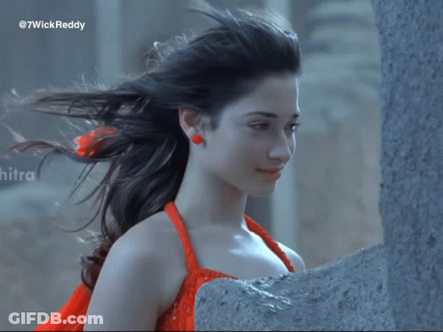 A Woman In A Red Dress Is Standing Next To A Wall With The Hashtag 7Wickreddy On The Bottom GIF