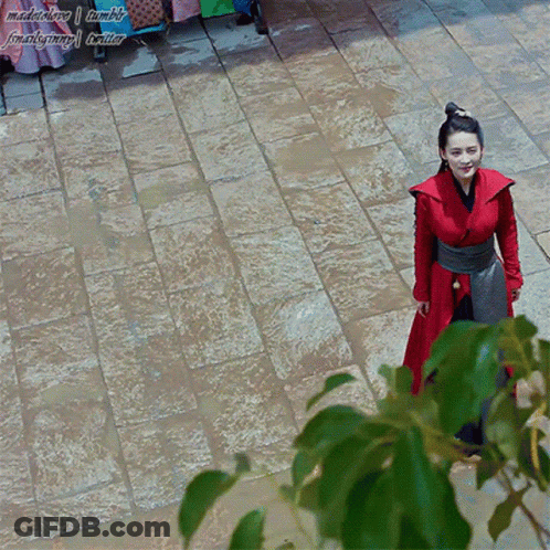 A Woman In A Red Dress Is Standing On A Brick Walkway With A Watermark That Says Madebylove Tumblr GIF