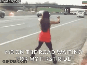 A Woman In A Red Dress Is Standing On The Side Of A Highway . GIF