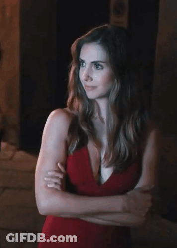 A Woman In A Red Dress Is Standing With Her Arms Crossed In Front Of A No Parking Sign GIF