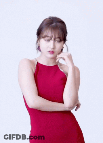 A Woman In A Red Dress Is Standing With Her Hands Crossed GIF