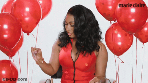 A Woman In A Red Dress Is Surrounded By Red Balloons With Marie Claire Written On The Balloons GIF