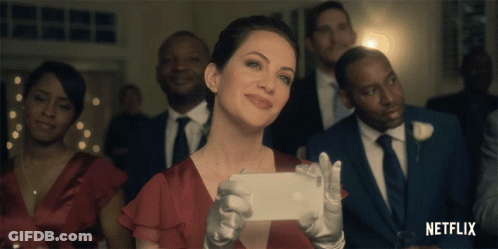 A Woman In A Red Dress Is Taking A Picture Of Herself With A Netflix Logo In The Background GIF