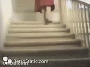 A Woman In A Red Dress Is Walking Down A Set Of Stairs With Retrostatic.com In The Corner GIF