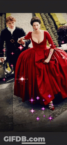 A Woman In A Red Dress Is Walking Next To A Man In A Black Suit GIF