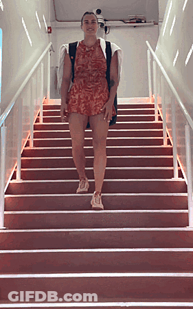 A Woman In A Red Dress Is Walking Up A Set Of Red Stairs GIF