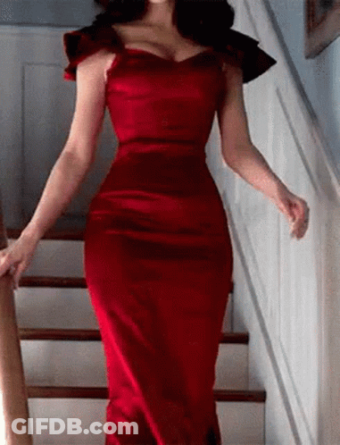 A Woman In A Red Dress Is Walking Up Stairs . GIF