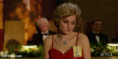 A Woman In A Red Dress Is Wearing A Tiara And Holding A Gold Medal .. GIF