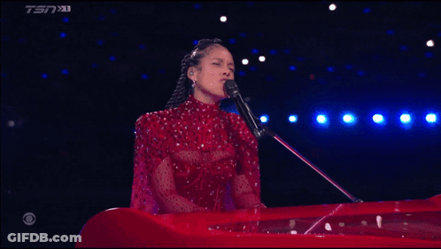 A Woman In A Red Dress Singing Into A Microphone With Tsn On The Bottom Right GIF