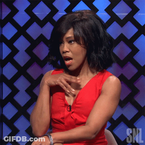 A Woman In A Red Dress Sitting In Front Of A Snl Sign GIF