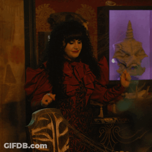 A Woman In A Red Dress Stands In Front Of A Display Case With A Skull In It GIF