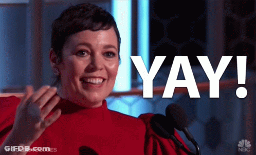 A Woman In A Red Dress Stands In Front Of A Microphone With The Word Yay In White Letters GIF