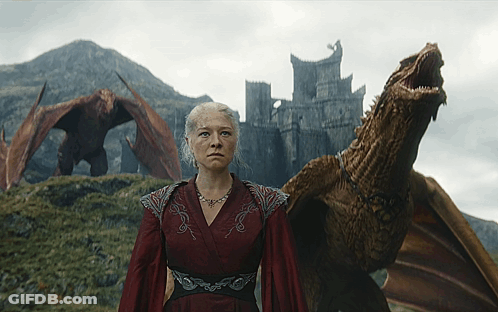 A Woman In A Red Dress Stands Next To A Dragon With A Castle In The Background GIF