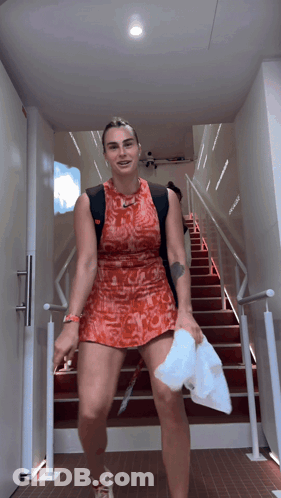 A Woman In A Red Dress Walking Down Stairs GIF